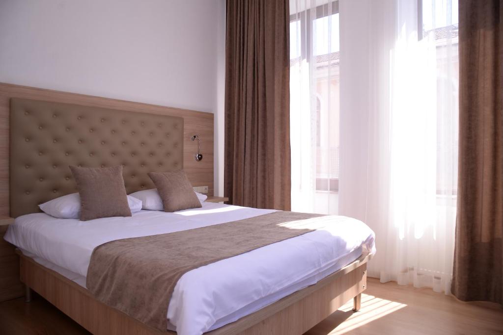 a bedroom with a large bed and a large window at Hotel Varios in Batumi