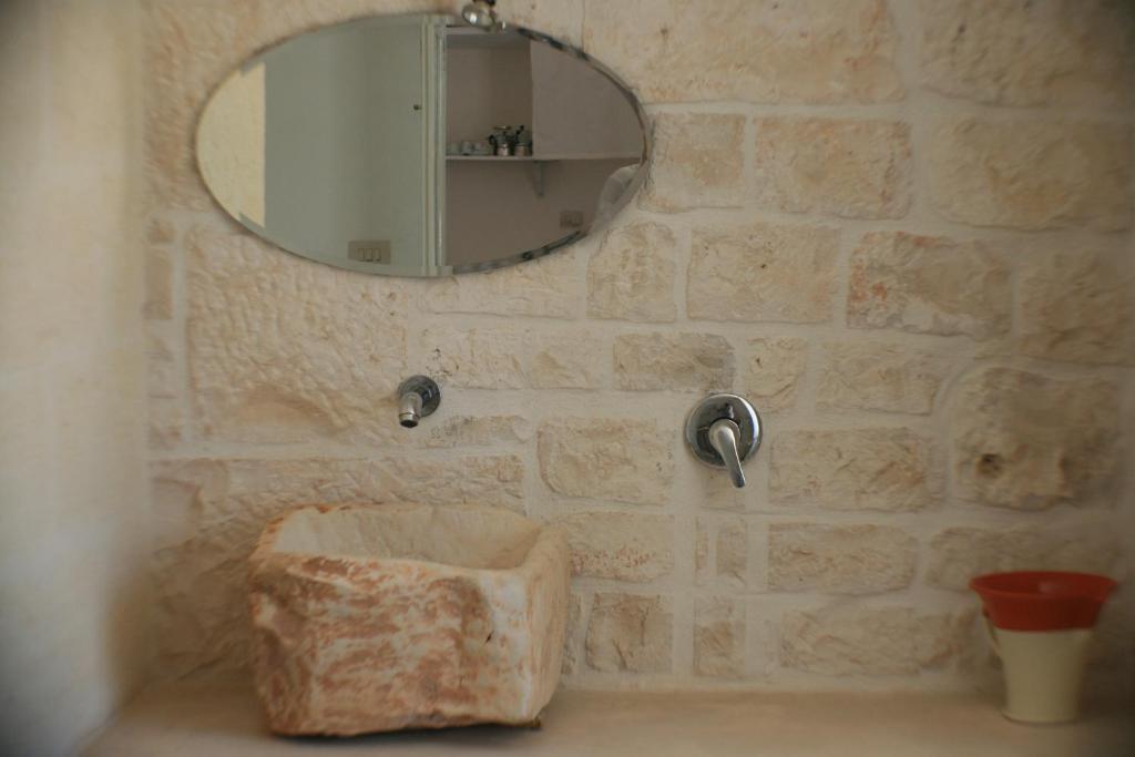 a bathroom with a mirror and a stone wall at Casolare Capitolo in Cisternino