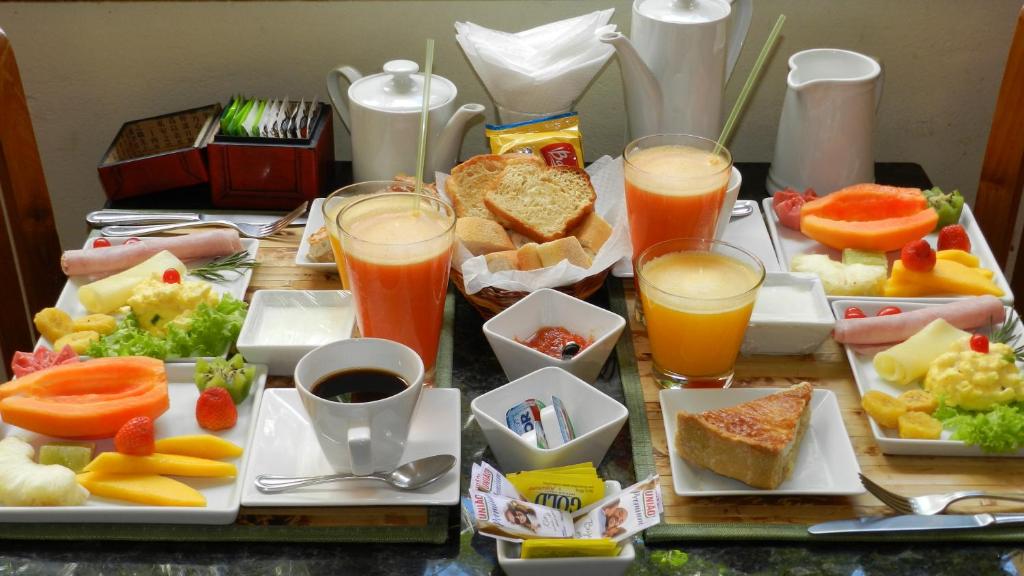 a table topped with plates of food and glasses of juice at Hotel Casa do Amarelindo in Salvador