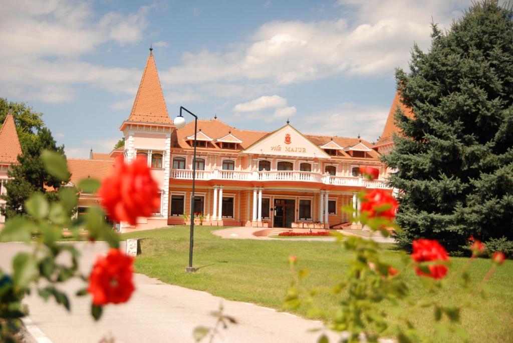 una casa grande con un patio con flores rojas en Hotel Villa Majur, en Subotica