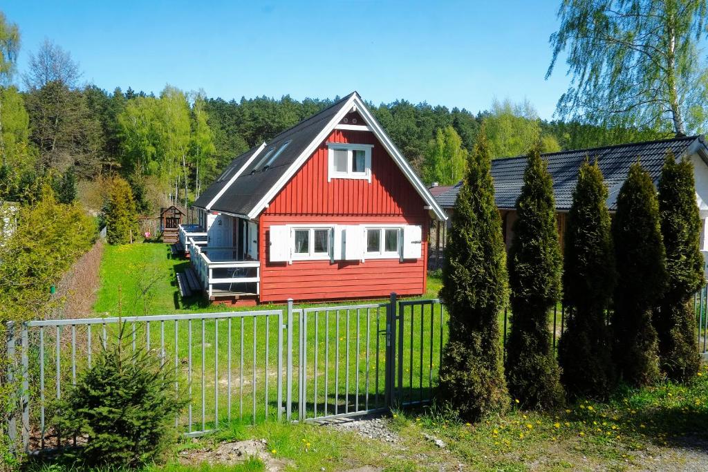 a red and white house with a fence at Domek Drewniany in Gdańsk