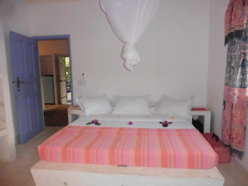 a bedroom with a bed with a striped mattress at Downtown Malindi Apartment in Malindi