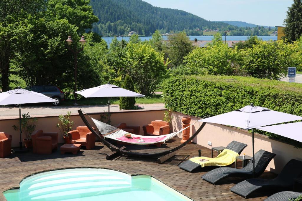 een hangmat en stoelen op een terras naast een zwembad bij Les Loges Du Parc in Gérardmer