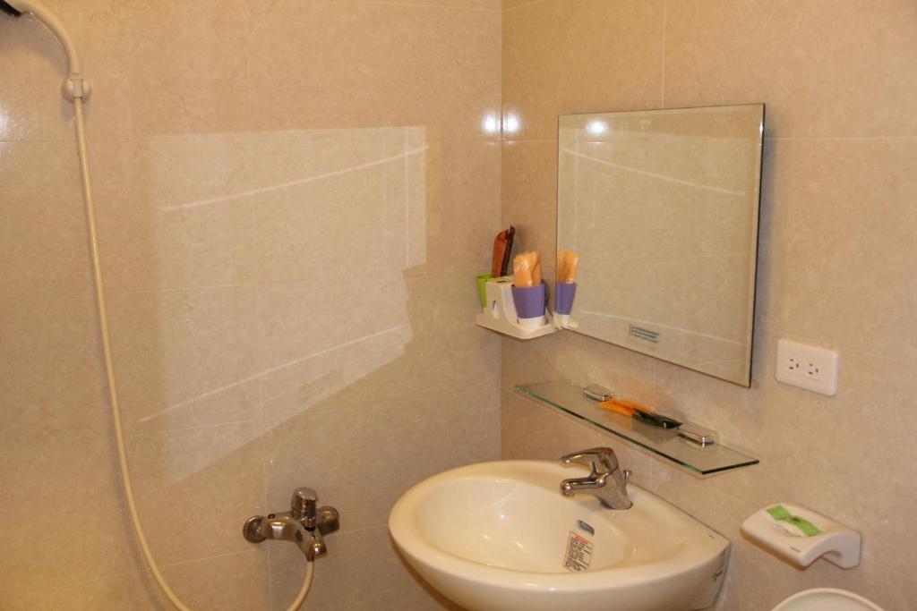 a bathroom with a sink and a shower with a mirror at 八八小屋心享民宿 in Jinning