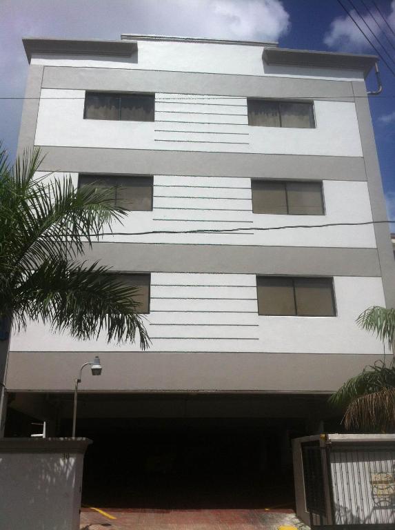a white building with a palm tree in front of it at Micro Hotel Condo Suites in Santo Domingo