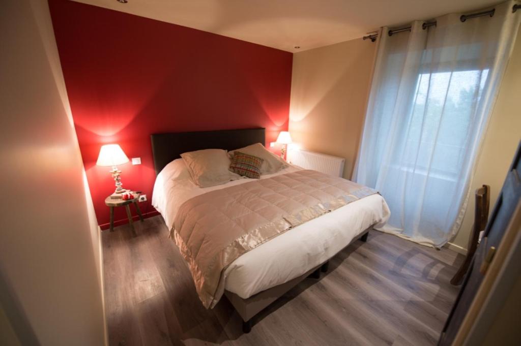 a bedroom with a large bed with a red wall at Gite De Charme Caussenard in Le Massegros