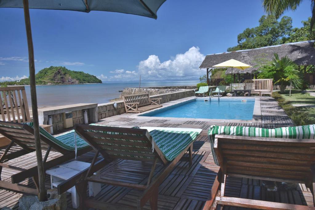 um resort com uma piscina e cadeiras e um guarda-sol em Ylang hôtel em Ambondrona