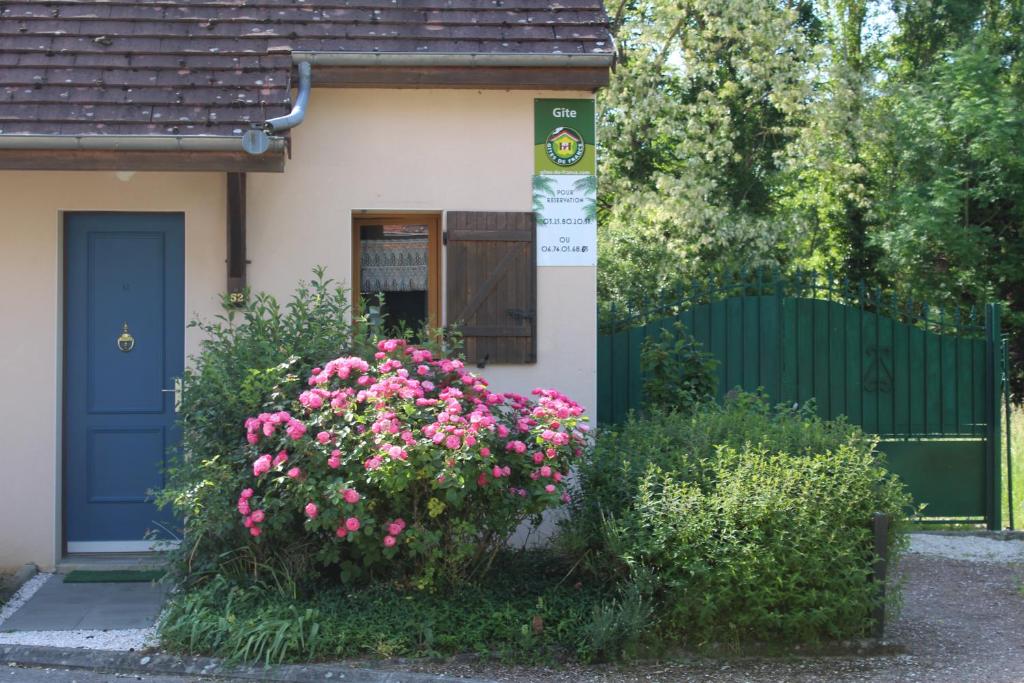 una casa con una porta blu e dei fiori rosa di Le Port Mesnil a Mesnil-Saint-Père
