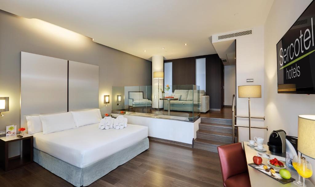 ビルバオにあるセルコテル コリセオのベッドとリビングルームが備わるホテルルームです。