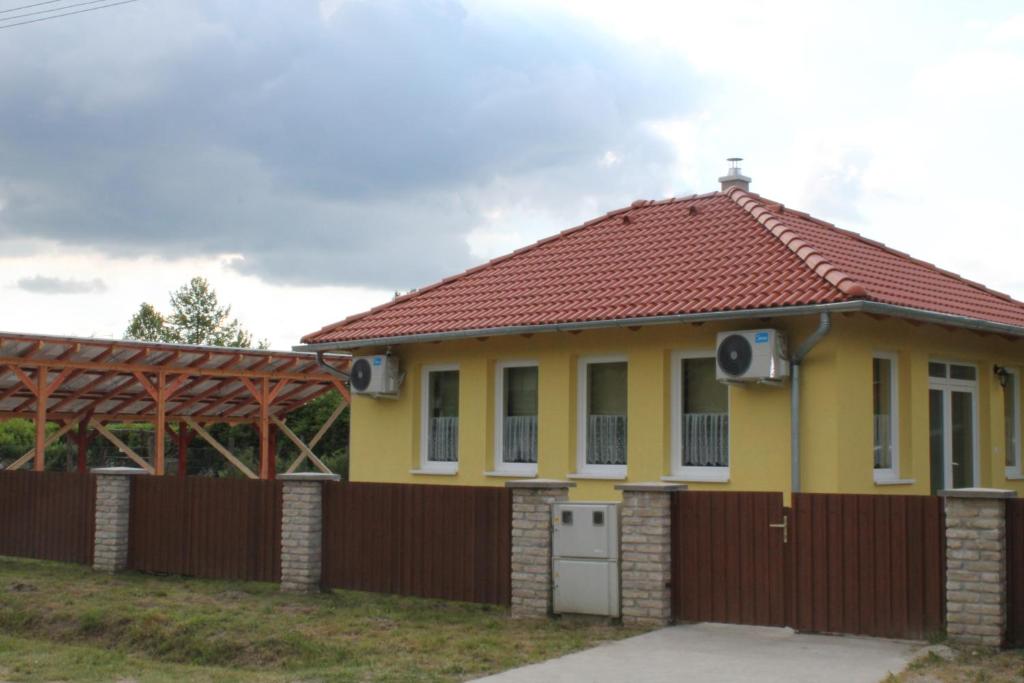 a small yellow house with a red roof at Ponty Orsó Vendégház in Nagybaracska