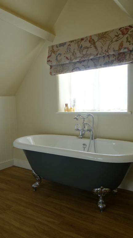 a large bath tub in a bathroom with a window at The Colesbourne Inn in Colesbourne