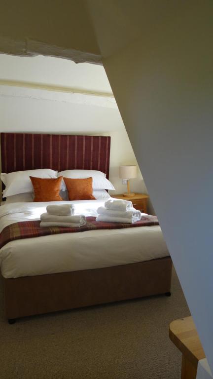 a bedroom with a large bed with orange pillows at The Colesbourne Inn in Colesbourne