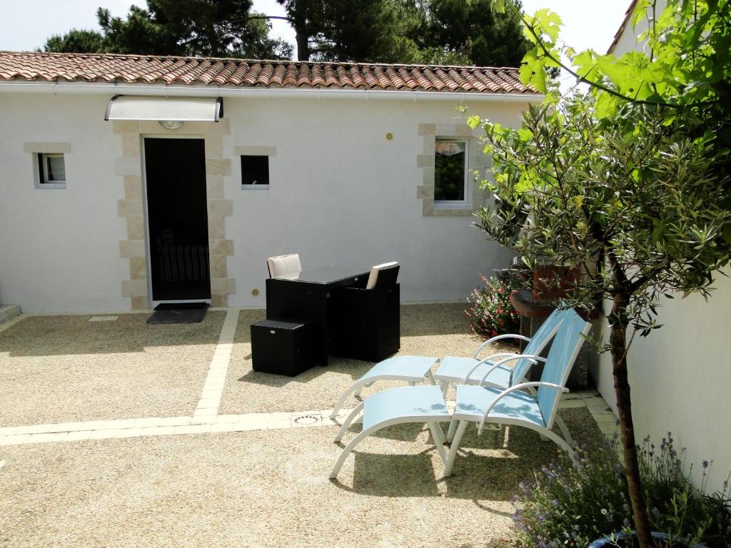 een patio met 2 stoelen en een huis bij La Petite Maison sur l'Ile de Ré in La Flotte