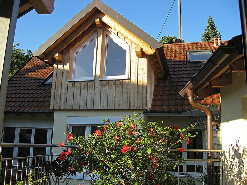 uma casa com uma janela e um arbusto com flores vermelhas em Die Sprachpension - The Language Guesthouse em Vogtsburg