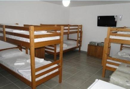 a room with three bunk beds and a flat screen tv at Spazio Itauna Hostel in Saquarema