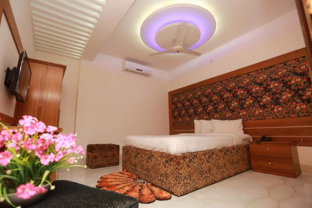 1 dormitorio con 1 cama, ventilador de techo y flores en Nagar Valley Hotel Ltd. en Dhaka