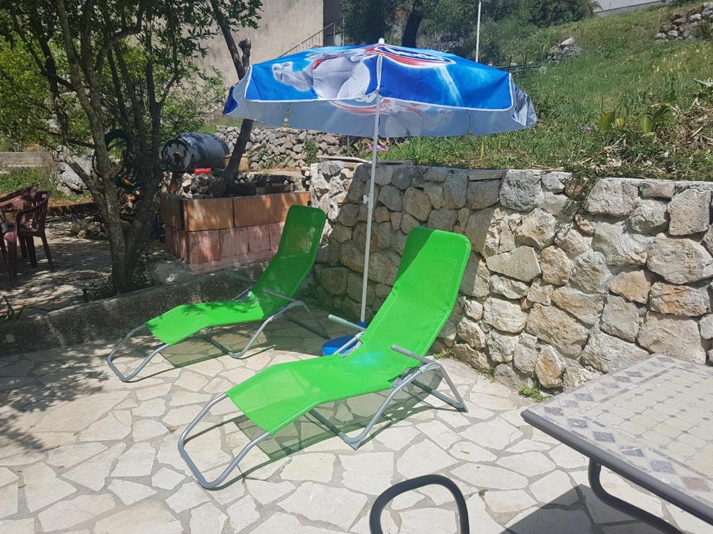 two green chairs and an umbrella on a patio at Apartment Manuela II in Ston