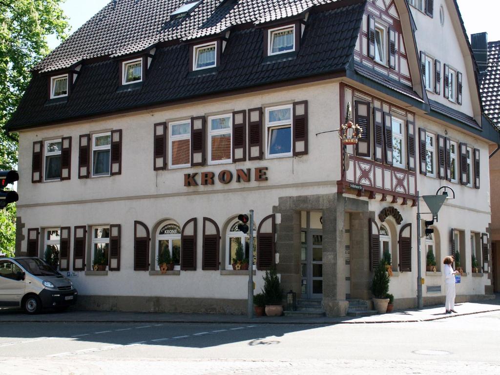 una mujer parada frente a un edificio de casas k en Restaurant Orakel, en Oberstenfeld