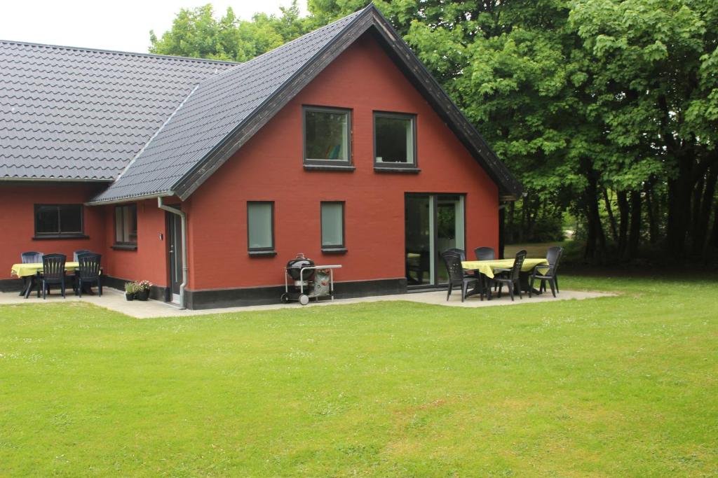 een rood huis met een tafel en stoelen ervoor bij Skovgårdens Apartment in Grindsted