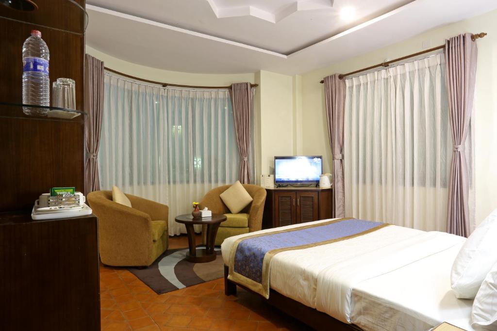 a hotel room with a bed and a tv at Dahlia Boutique Hotel in Pokhara