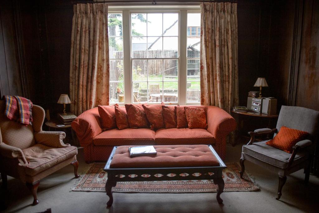 a living room with a red couch and a window at Bank House B&B in Bishops Castle