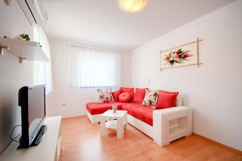 een woonkamer met een rode bank en een tv bij Apartments Dario in Medulin