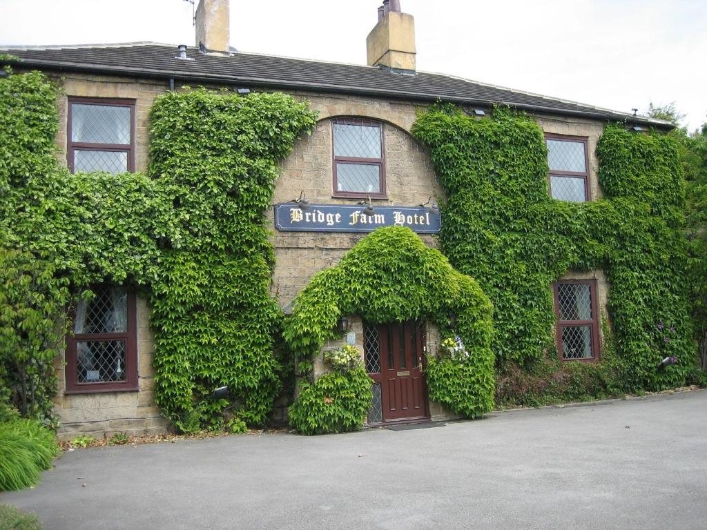 a building covered in ivy with a sign on it at Bridge Farm Hotel in Leeds