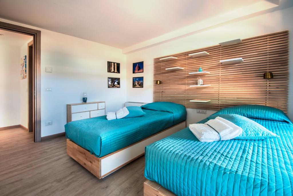 two beds in a bedroom with blue sheets at Alla Corte Maqueda in Palermo