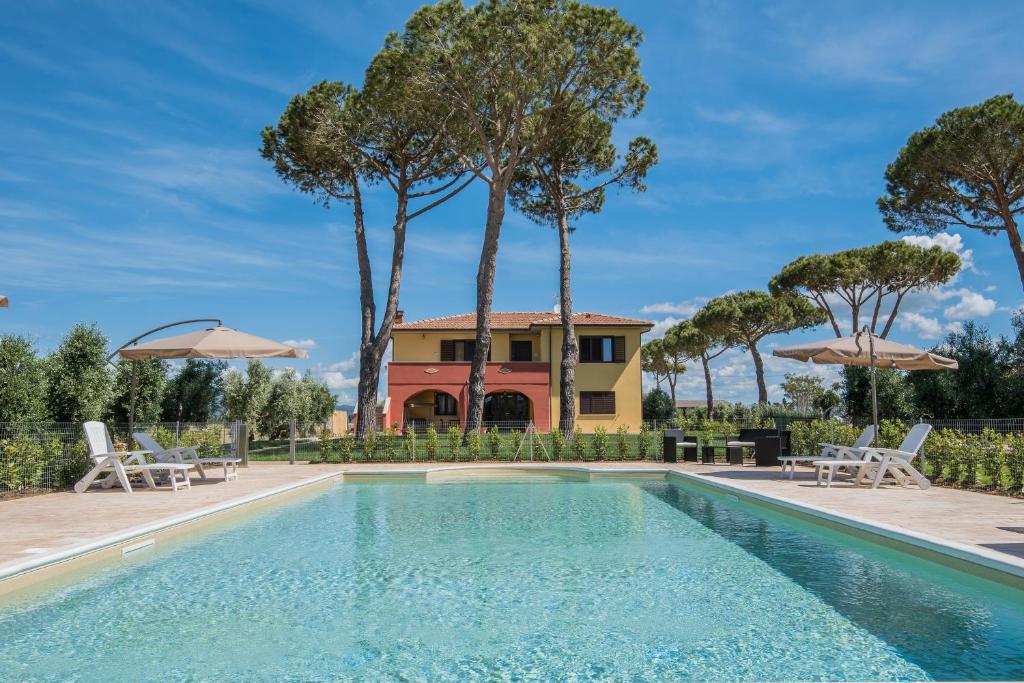 una piscina con sedie e ombrelloni di fronte a una casa di Agriturismo Podere Nonno Gino a Casa Franciana