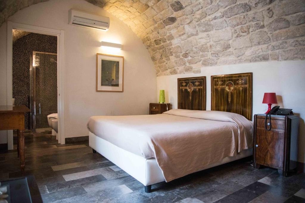 a bedroom with a large bed and a stone wall at Hotel Dell'Orologio in Ragusa