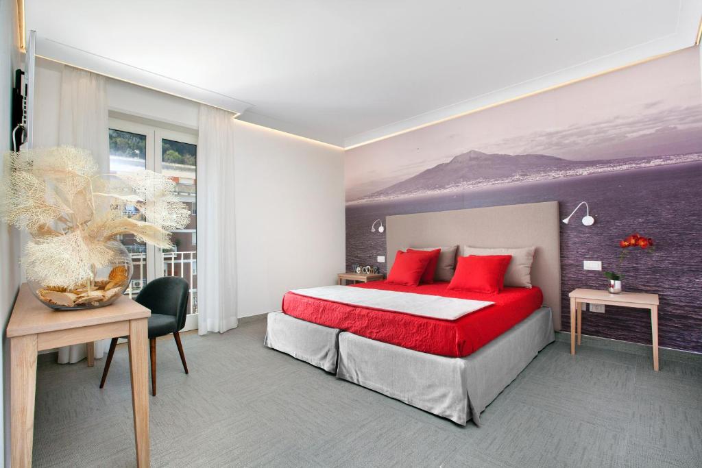 Ulisse Apartment في سورينتو: غرفة نوم مع سرير مع وسائد حمراء ومكتب