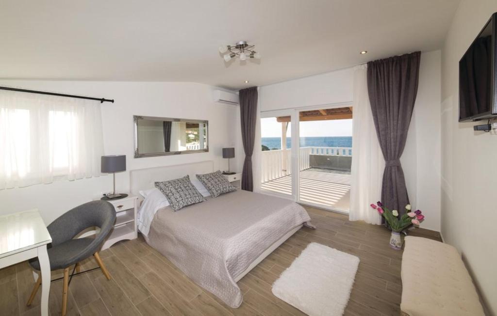 Schlafzimmer mit einem Bett, einem Schreibtisch und einem Balkon in der Unterkunft Luxury villa Vela Rina in Drvenik Mali