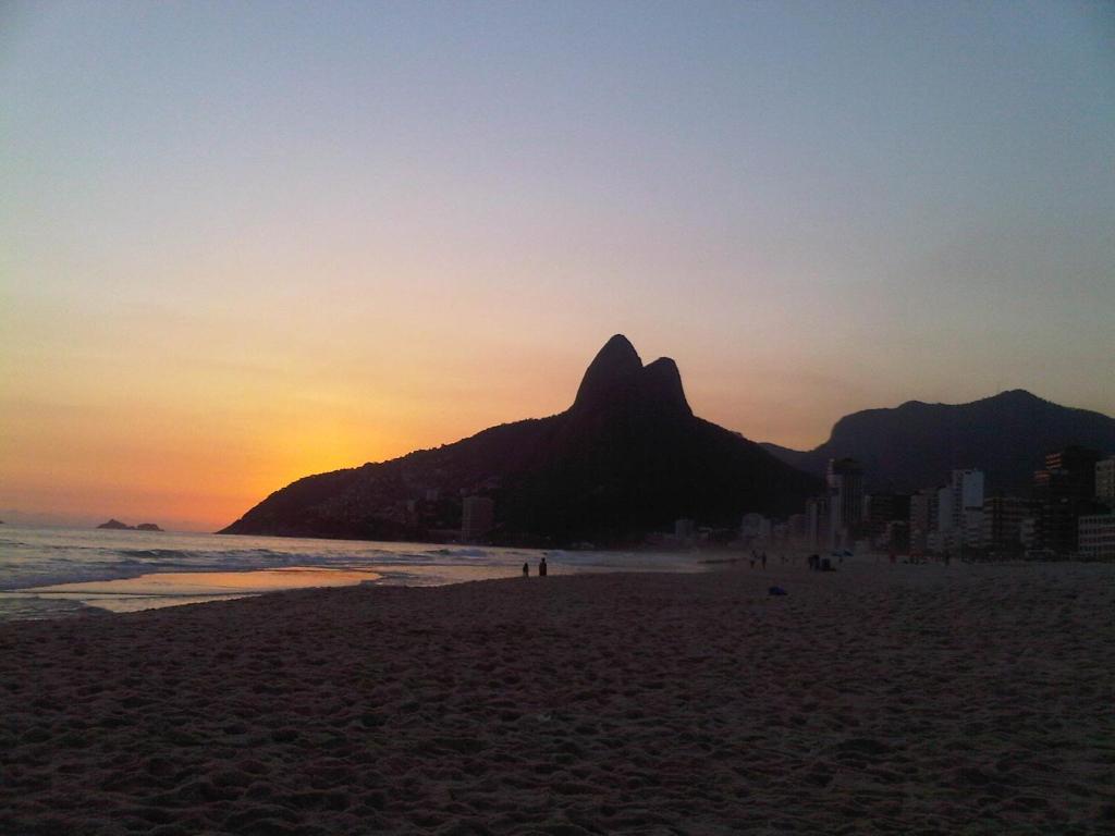 a sunset on a beach with a mountain in the background at Hotel Ferreira Viana in Rio de Janeiro