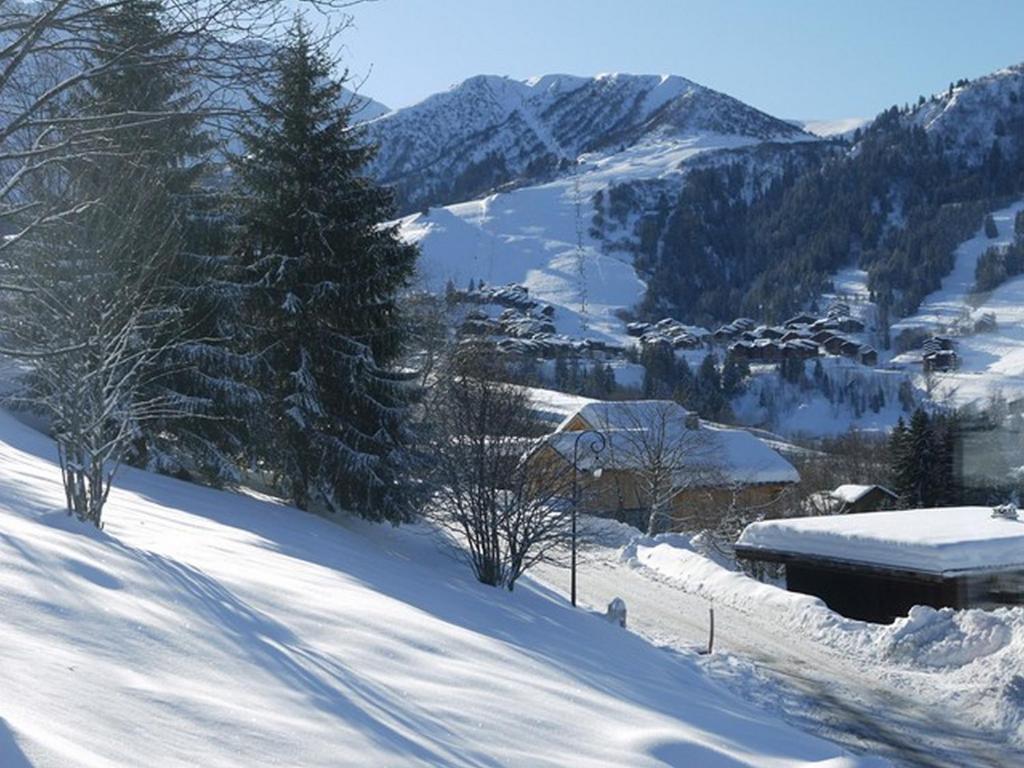 une montagne enneigée avec une ville au loin dans l'établissement Chalet la Ravine, à Valmorel