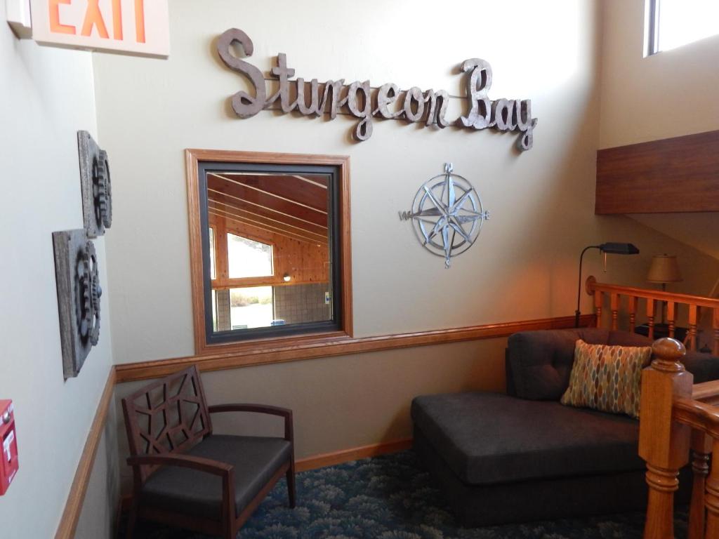 a living room with a couch and a sign on the wall at AmericInn by Wyndham Sturgeon Bay in Sturgeon Bay