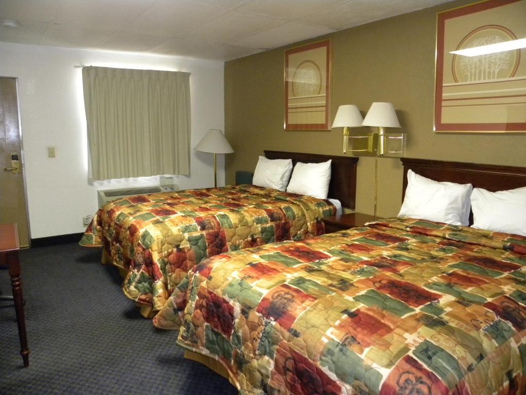 een hotelkamer met 2 bedden en kleurrijke dekens bij Guest Inn Rogers in Rogers