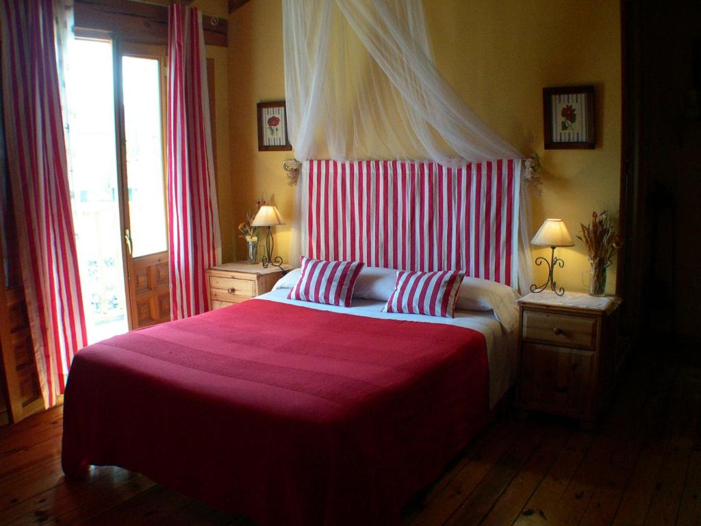 a bedroom with a large bed with a red blanket at Casa rural Estrella Polar II in Arcones