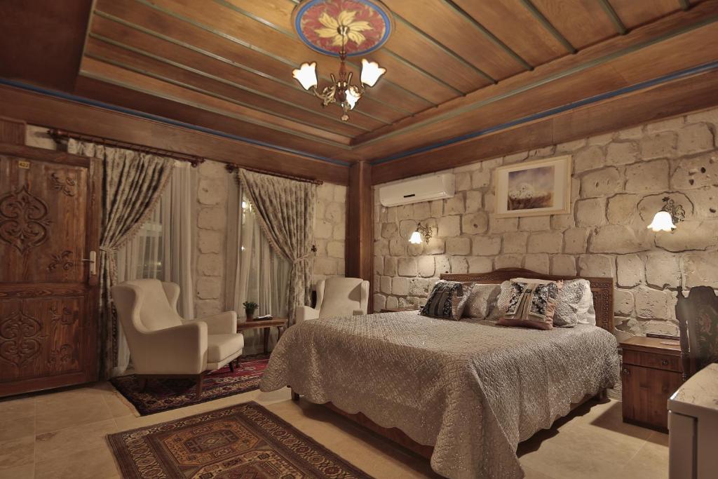 a bedroom with a bed and a stone wall at Guzide Cave Hotel in Göreme