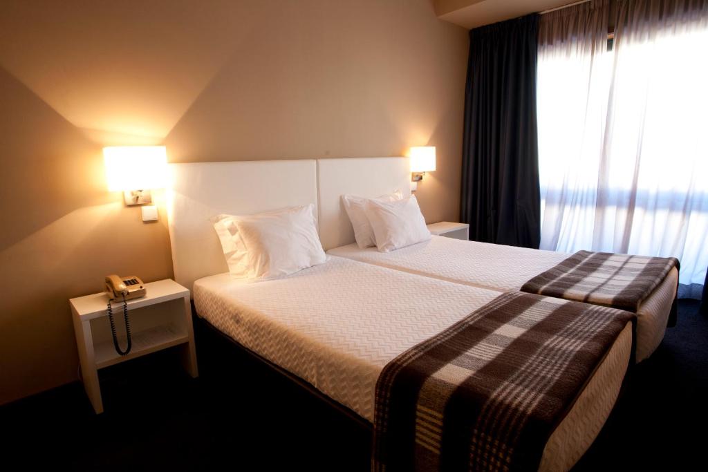 Habitación de hotel con cama y ventana en Porto Antas Hotel en Oporto