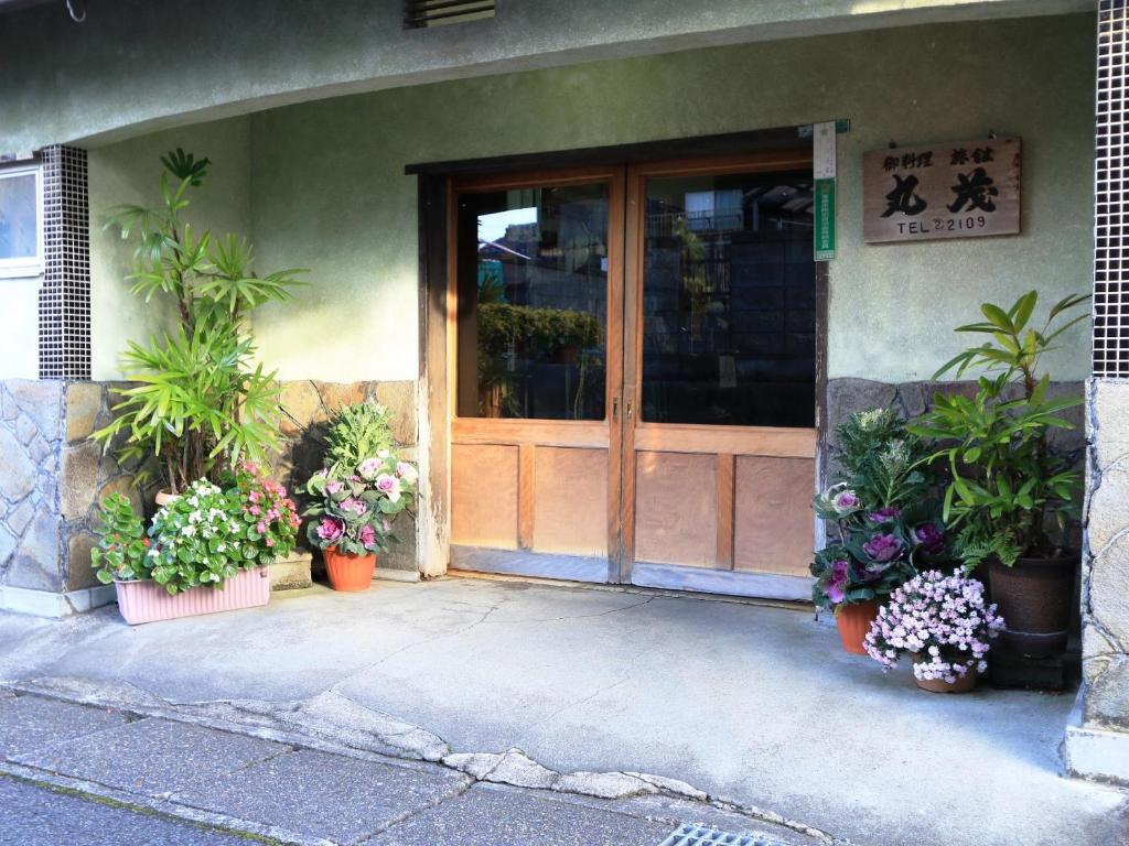 高島市的住宿－料理旅館丸茂，一座有植物盆的建筑的前门