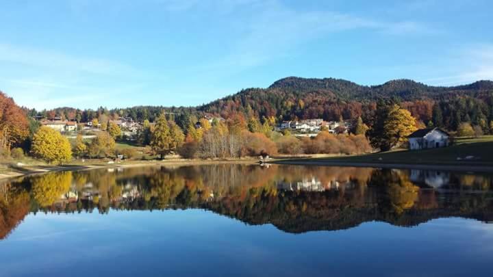 vistas a un lago con árboles y casas en Haus Green & Spa Angelika Trentino, en Lavarone