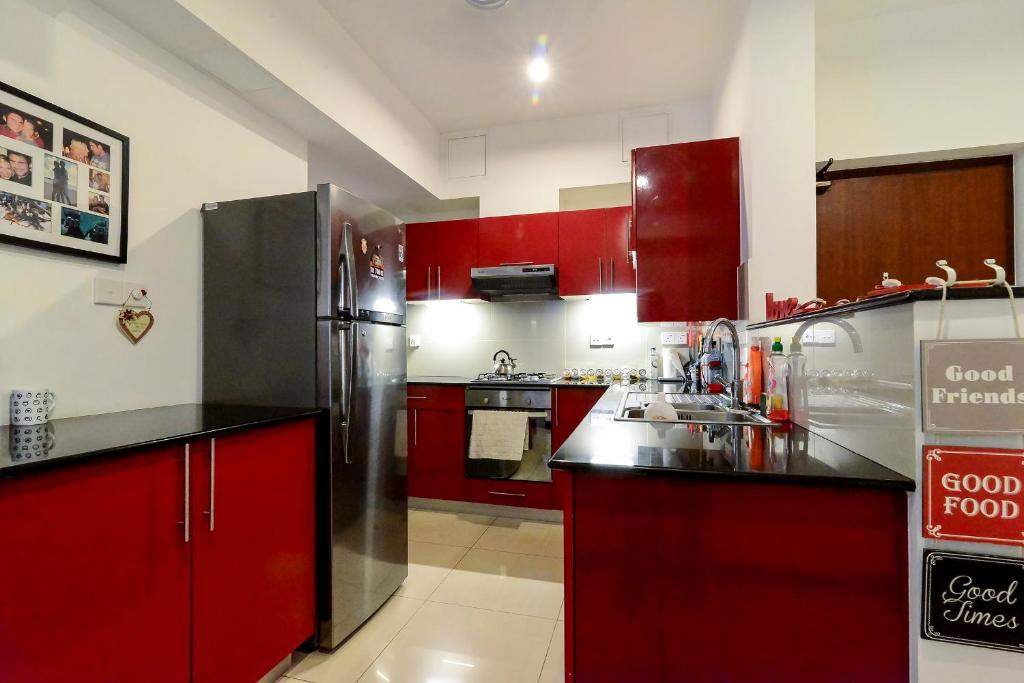 una cucina con armadi rossi e frigorifero in acciaio inossidabile di On 320 Apartment a Colombo
