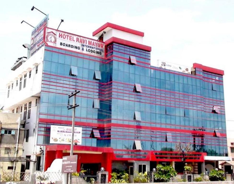 a large glass building with a sign on it at Hotel Ravi Mayur International in Chitradurga