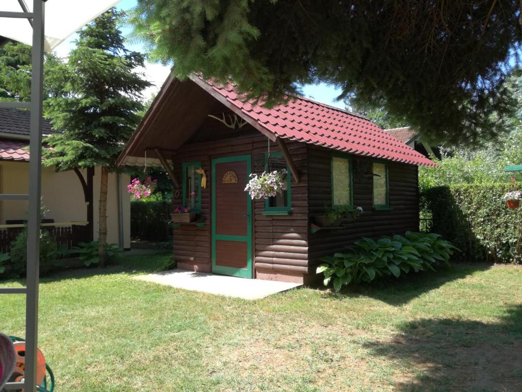 una pequeña casa con techo rojo y puerta verde en Stara Breza 1 Rooms, en Palić