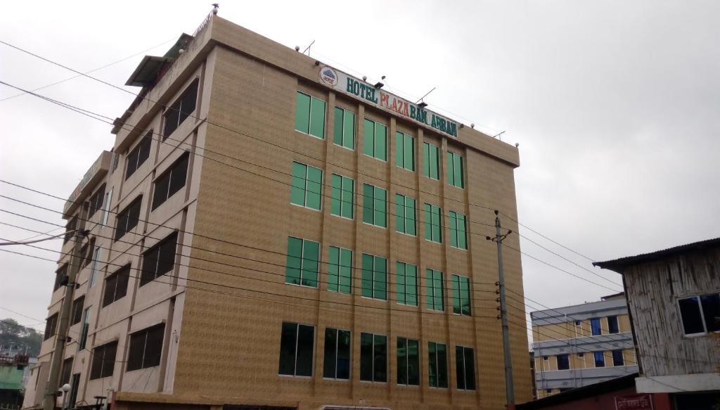 a building with green windows on the side of it at Hotel Plaza in Bāndarban