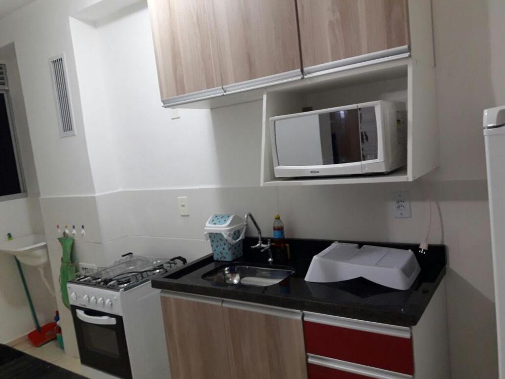 a small kitchen with a sink and a microwave at Condominio Mar de Gales in Macaé
