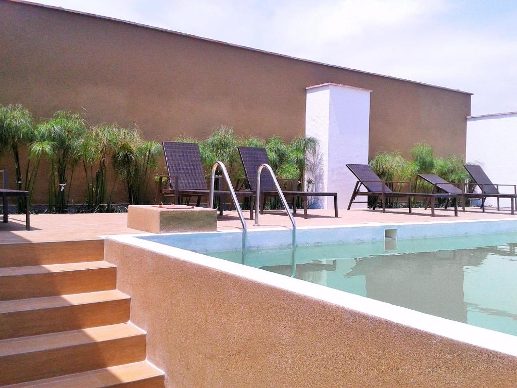 a swimming pool with chairs next to a building at Peru Premium Aparts in Lima