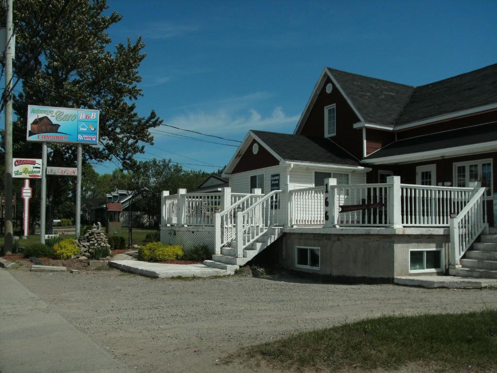 a house with a porch with a white railing at Auberge Chez Caro in Sacré-Coeur-Saguenay