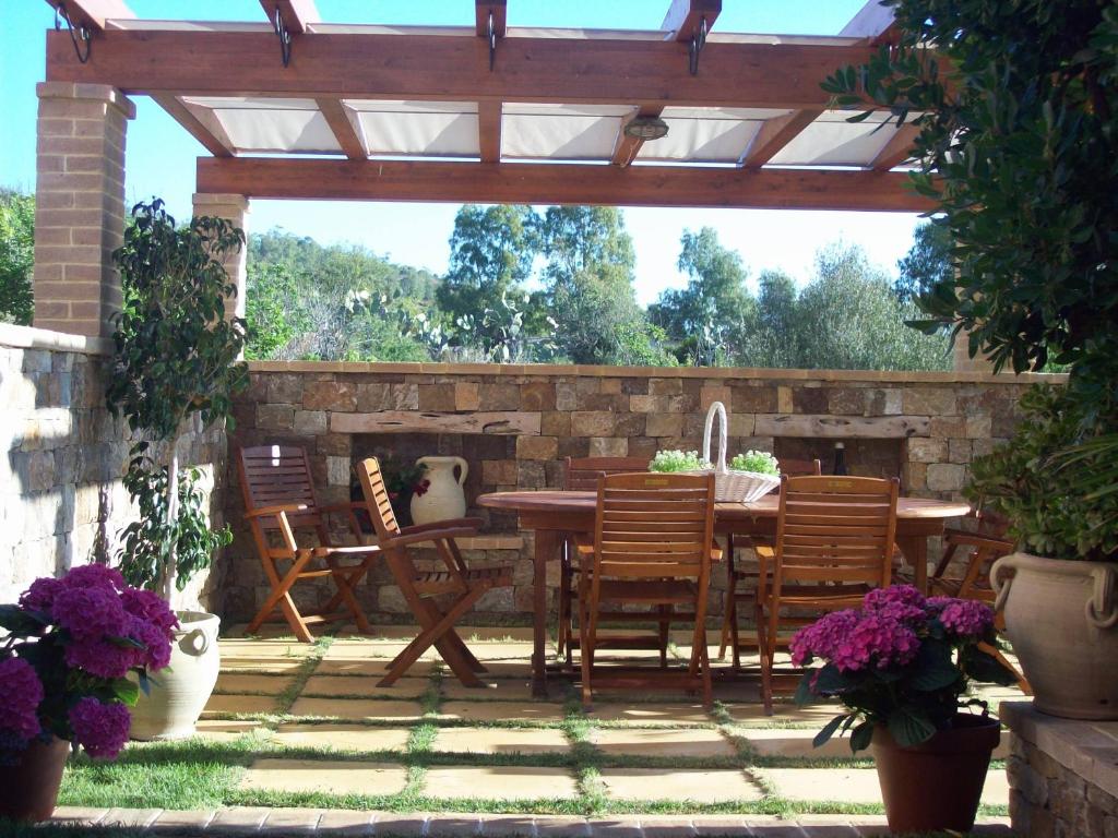 a patio with a wooden pergola with a table and chairs at Affittacamere Belvedere La Peonia in Villaputzu