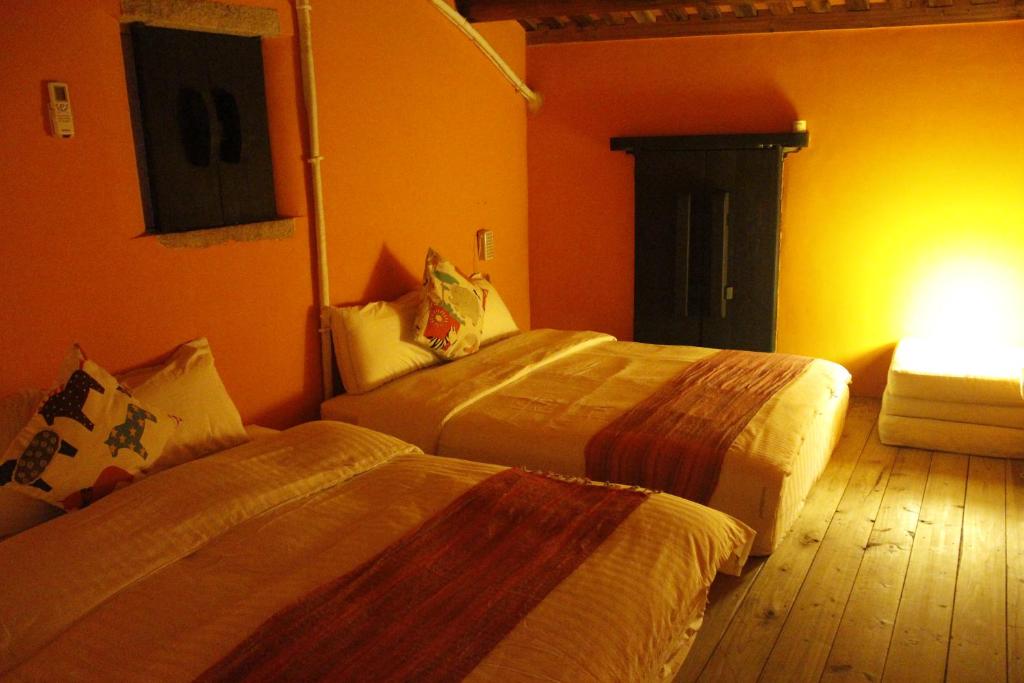 two beds in a room with orange walls at PianoPiano B&amp;B in Jincheng